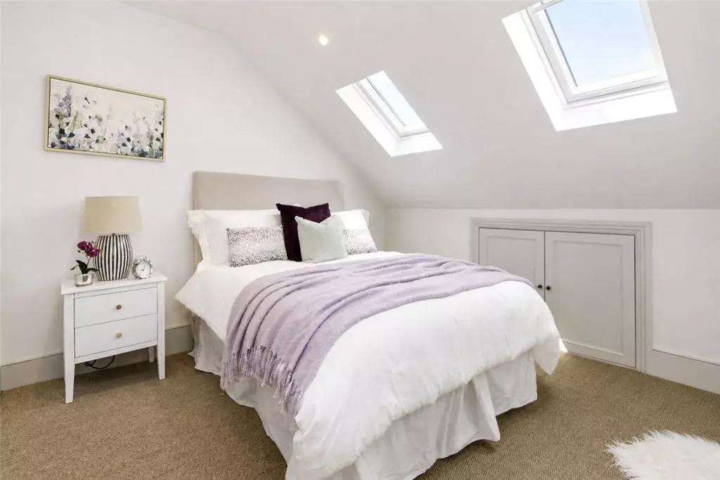 Furnished loft bedroom with two rooflights, fitted storage and a sloping ceiling